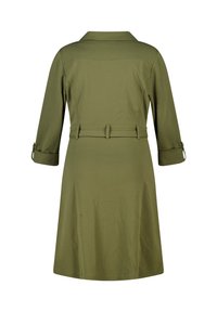 Olijfgroene jurk met een kraag, driekwart mouwen, een ceintuur in de taille en een uitlopende rok met een zachte textuur.