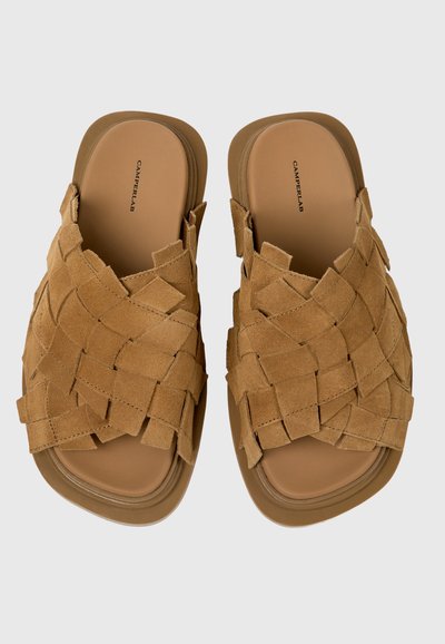 Sandalias marrones de ante con diseño sin cordones, tiras tejidas y plantillas acolchadas, mostradas lado a lado sobre un fondo claro.