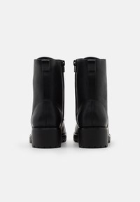Botas de cuero negras hasta el tobillo con un acabado suave, cremalleras laterales y suelas gruesas con dibujo. Presentan punta redondeada y un diseño minimalista.