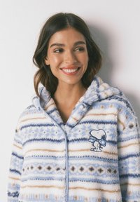 Fuzzy capuchonbadjas met een lichtblauw en witte gestreepte print en bruine accenten. Borduursel van Snoopy op de borst. Zachte textuur.