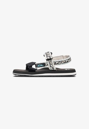 Sort-hvid mønstret sandal med justerbare stropper, tekstureret sål og kontrasterende hvid mellemsål. Letvægtsdesign til udendørs brug.