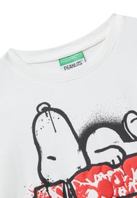 Weißes T-Shirt mit einem Schwarz-Weiß-Snoopy-Grafik, roten abstrakten Formen und einem "United Colors of Benetton"-Label im Kragen.