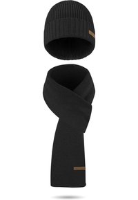 Schwarzes Strickmütze und Schal-Set mit gerippter Textur, beide Teile mit einem Streifen aus braunem Leder und Branding. Weiches, warmes Material.