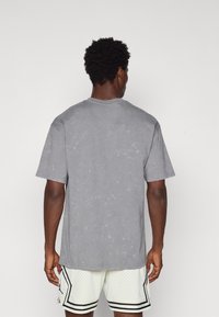 Grå bomulds t-shirt med afslappet pasform, korte ærmer og en falmet tekstur. Udhugningen er ribbet, og den har ingen grafik eller mønstre.