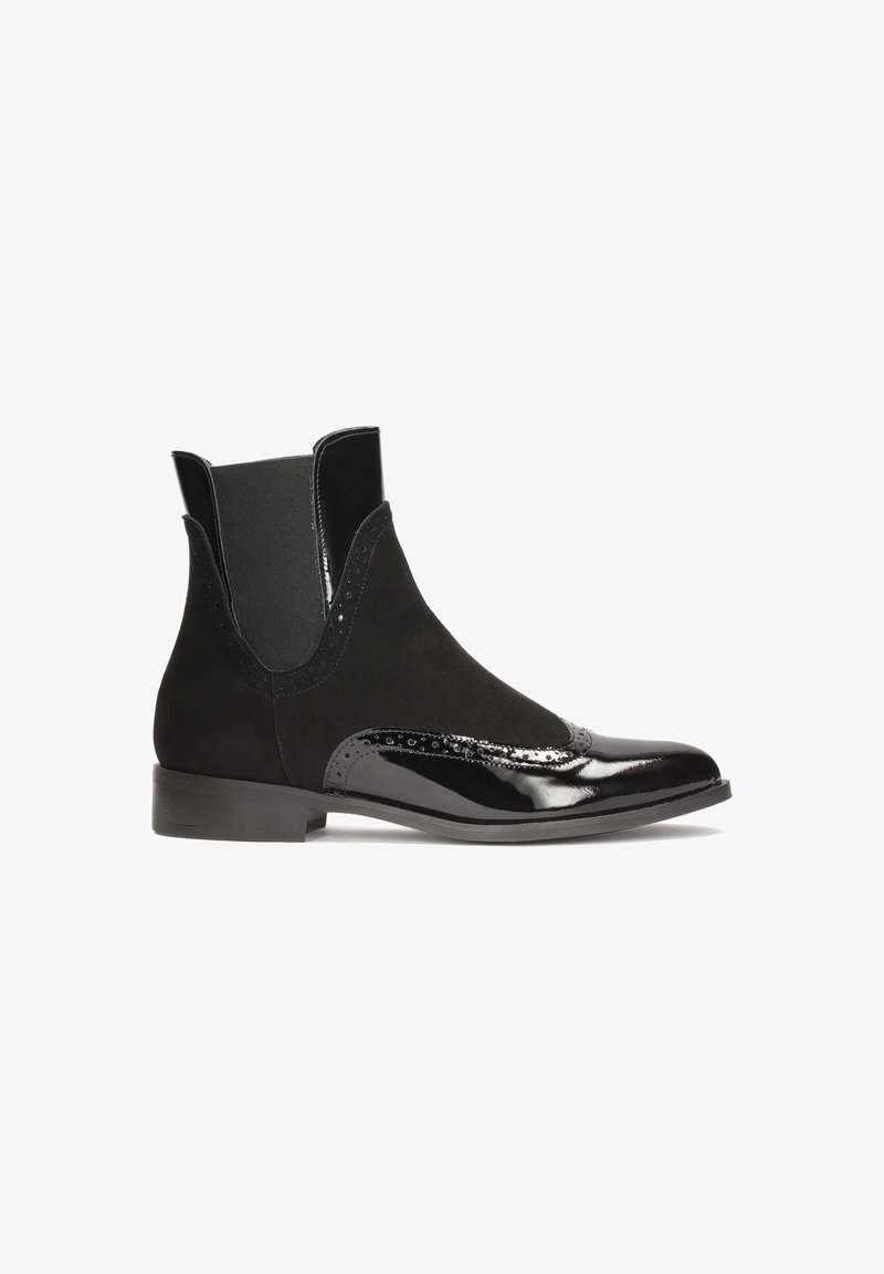 Bottine noire à la cheville avec panneaux latéraux élastiques, détails brogue et mélange de suède mat et de cuir verni brillant.