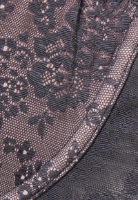 Pizzo nero con un motivo floreale su uno sfondo rosa, bordato da un tessuto scuro e liscio. Dettagli intricati e testurizzati visibili.