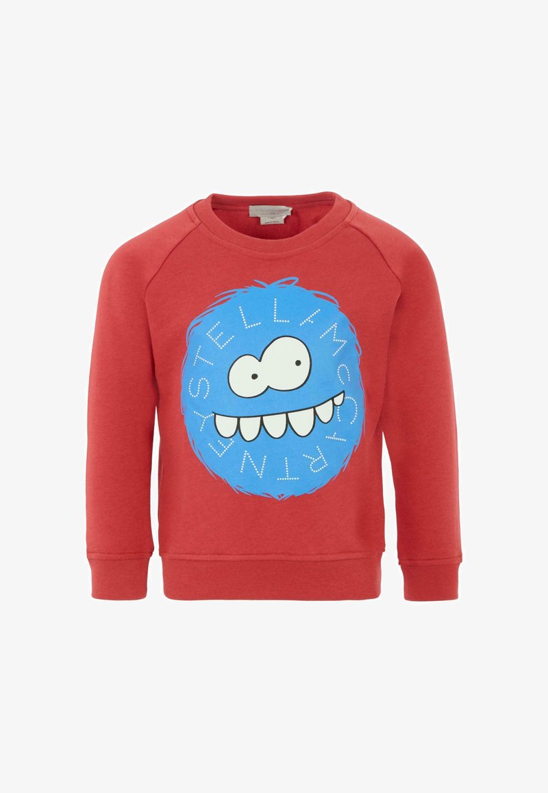 Sweatshirt rouge avec un grand graphisme circulaire bleu présentant un visage, avec de grands yeux et un large sourire. Encolure ronde et poignets côtelés.