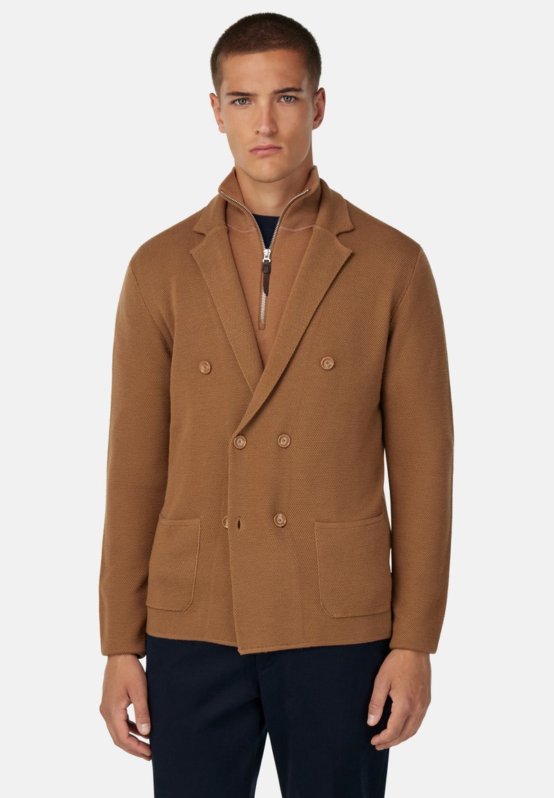 Blazer marrón de doble botonadura con un patrón de punto texturizado, que cuenta con dos bolsillos frontales y un cuello con cremallera. Un ajuste moderno y ajustado.