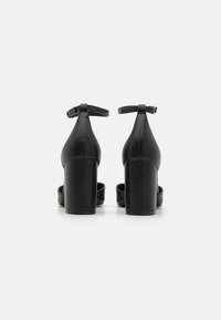 Black high-heeled sandals with a smooth leather finish, ankle strap, and square heel design. Open toe and minimalistic silhouette.