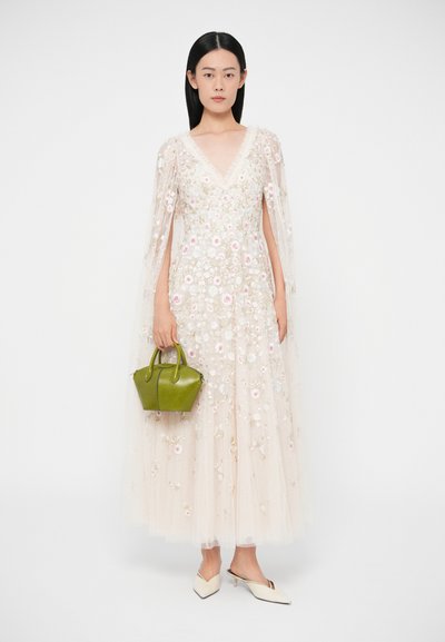 Dlhé, priesvitné šaty s kvetinovou výšivkou v svetlo béžovej farbe, s výstrihom do V a rukávmi pripomínajúcimi plášť. Doplniteľné malou zelenou kabelkou a bielymi mulemi.