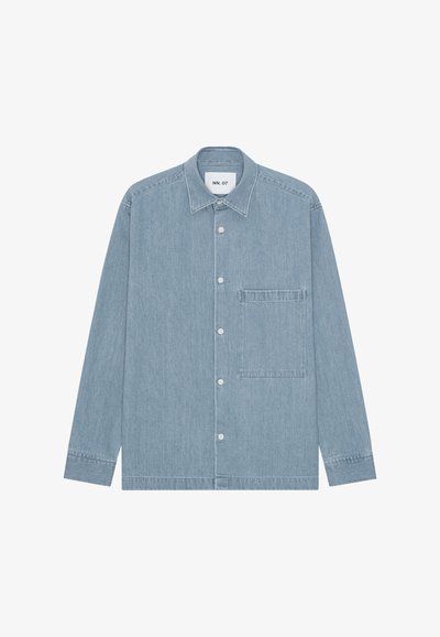 Chemise en denim bleu clair à boutons, manches longues, une poche poitrine à gauche et un col, posée à plat sur fond blanc.