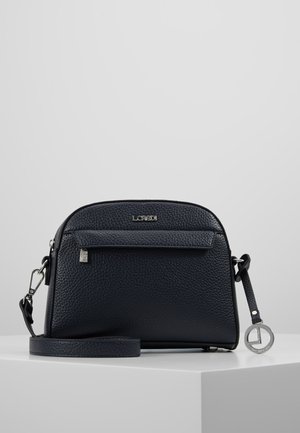 Black textured leather crossbody bag with front zip pocket, silver logo plate, adjustable strap, and round silver brand charm on white surface.