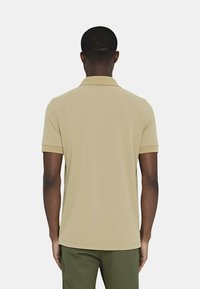 Polo beige con maniche corte e colletto. Texture liscia e dettagli di cucitura sottili, visto da dietro.