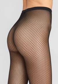 Czarne rajstopy z siateczki w heksagonalny wzór, gładka tekstura i falbaniasty pas w talii, zaprojektowane z myślą o ścisłym dopasowaniu.