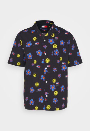 Chemise noire à manches courtes boutonnée avec des fleurs bleues et orange, des visages souriants jaunes et de petits logos rectangulaires rouges, blancs et bleus.
