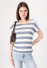Stripete t-skjorte i hvit og blå med løs passform, rund hals og korte ermer. Kombinert med lyseblå jeans og en liten brun lærveske.