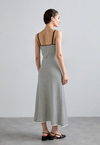 Gestreiftes Baumwollkleid mit dünnen schwarzen Trägern, einem taillierten Oberteil und einem ausgestellten Rock. Die Streifen sind schwarz und weiß, mit einer glatten Textur.