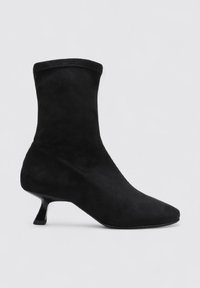 Black suede ankle boot with a pointed toe, sleek design, and a distinctive hourglass heel. Smooth texture and minimal stitching details.