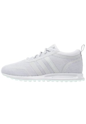 Hvid atletisk sneaker i mesh med grå accenter, tre striber på siden, "LOS ANGELES" tekst og en polstret sål med slidbanemønster.
