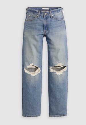 Jeans di denim blu con gambe dritte e grandi strappi orizzontali su entrambe le ginocchia, mostrati su uno sfondo semplice.