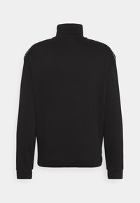 Sweat-shirt noir à manches longues avec col montant vu de dos, avec un détail subtil de rayure blanche le long des épaules.