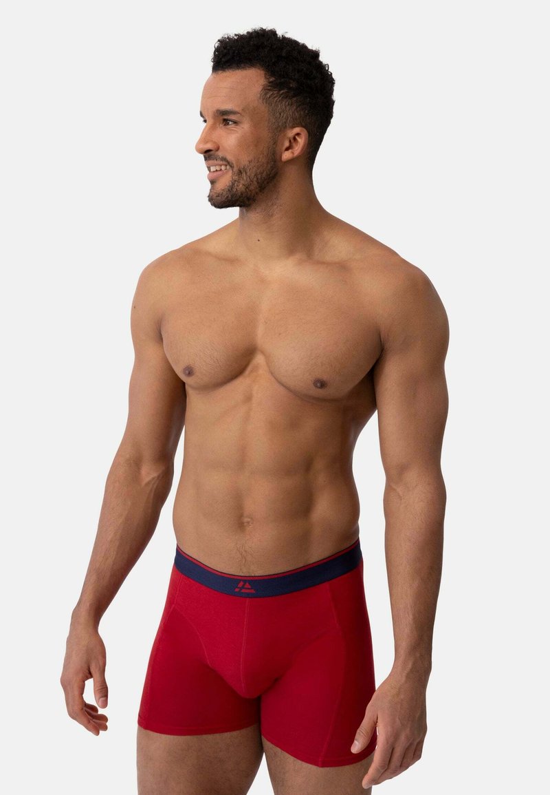 Boxer da uomo rossi realizzati in tessuto morbido con un elastico navy in vita che presenta un logo. Progettati per offrire comfort e una vestibilità aderente.