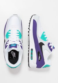 Les baskets Nike Air Max 90 blanches et violettes sont composées de mesh et de cuir, avec un swoosh noir, des accents turquoise et une unité d'air visible.