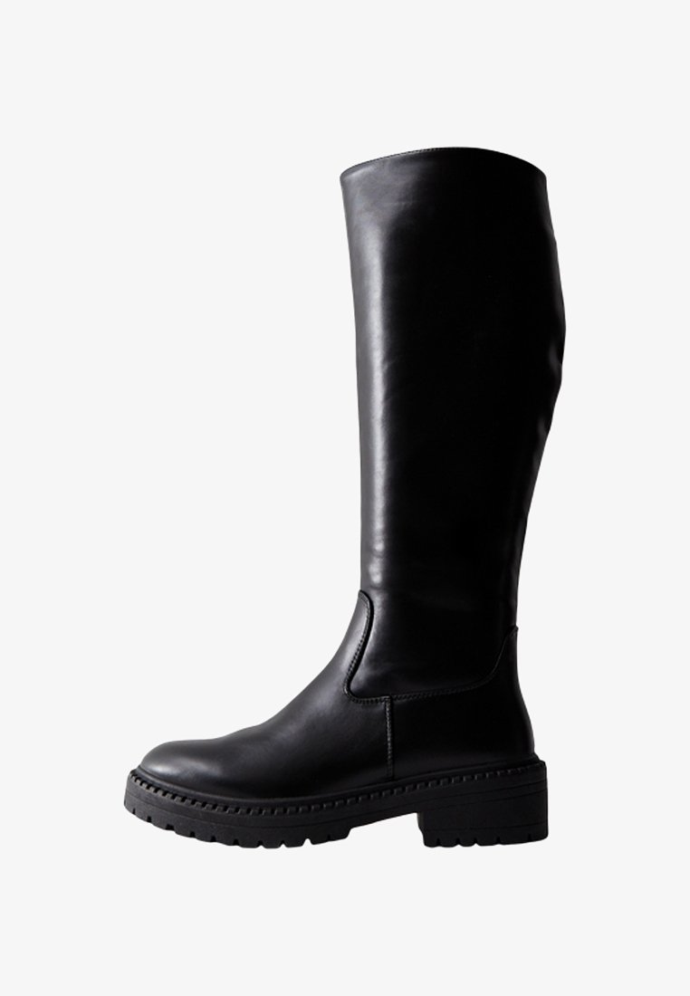 Botte en cuir noire montant jusqu'au genou avec une semelle épaisse et robuste, un bout arrondi et un petit talon carré, vue de profil sur un fond blanc.