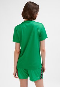 Zielony sportowy t-shirt z krótkim rękawem, wykonany z gładkiego, oddychającego materiału, w zestawie z dopasowanymi zielonymi spodenki z wzorzystym detalem po bokach.