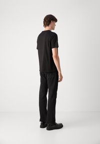 Black cotton t-shirt with a crew neck, paired with black denim jeans. The outfit features a relaxed fit and solid color design.