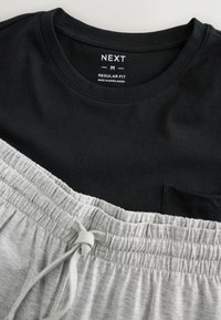 Čierne tričko s krátkym rukávom a okrúhlym výstrihom, doplnené sivými kraťasmi na šnúrku. Mäkká bavlnená látka s textúrovaným pásikom a detailmi na vreckách.