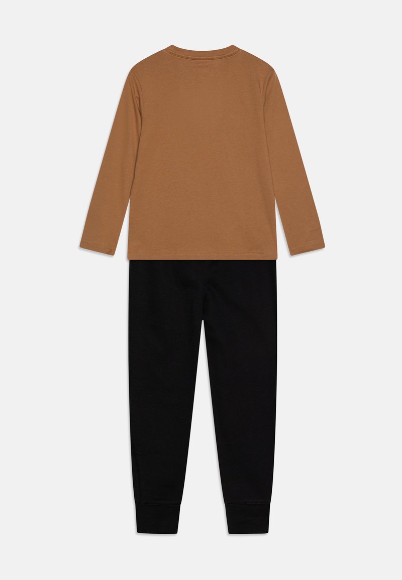 Set di camicia a maniche lunghe marrone e pantaloni neri. La camicia ha un coltondo e una consistenza morbida, mentre i pantaloni sono aderenti con polsini elasticizzati.