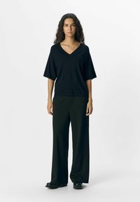 Black V-neck t-shirt with short sleeves, paired with wide-leg black trousers. Smooth texture; simple design without patterns or accents.