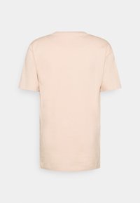 Ljusbeige bomulls-T-shirt med rund hals och korta ärmar, med en avslappnad passform och ett enkelt utseende utan synliga logotyper eller mönster.