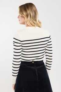 Top blanco de manga larga con rayas horizontales en navy. Cuello redondo y textura acanalada. Combinado con una falda de pana oscura con cremallera.