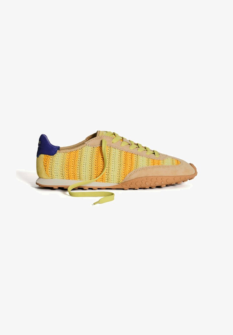 Zapatilla de cordones con parte superior de punto en amarillo y verde, detalles de ante y suela de goma marrón claro con agarre texturizado.
