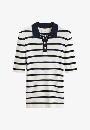 Polo blanc à manches courtes en tissu côtelé avec rayures horizontales bleu marine, col bleu marine et trois boutons dorés sur la patte de boutonnage.