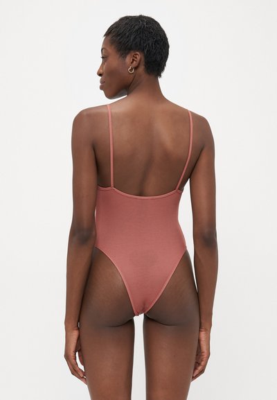 Ribbed one-piece swimsuit in dusty rose with thin straps and high-cut leg openings, featuring a low back design. Smooth texture.