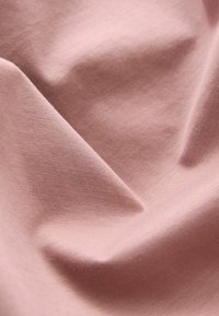 Lys rosa bomuldsstof med en glat tekstur, der viser subtile folder og en blød fald. Ingen mønstre eller synligt hardware.