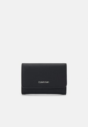 Black leather wallet with a fold-over flap, featuring a silver "Calvin Klein" logo on the front. Smooth texture with clean lines.
