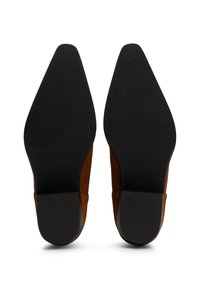 Chaussures à talons en daim marron avec un bout pointu et une semelle en caoutchouc noir. Présente une semelle texturée pour une meilleure adhérence et des bords lisses.