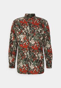 Overhemd met knopen in een camouflagepatroon met groene, rode en beige tinten. Gemaakt van zachte stof en voorzien van zijzakken en knoopsluitingen.