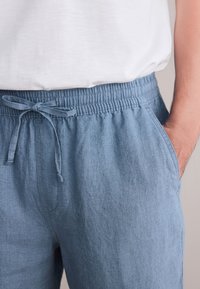 Pantaloncini azzurri chiaro, dalla texture strutturata con elastico in vita e coulisse. Dotati di tasche laterali e vestibilità comoda. Realizzati in tessuto morbido e traspirante.