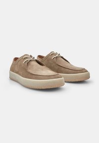 Zapatos de ante beige con forma redondeada, suela de goma texturizada de color claro y cordones finos. Diseño minimalista sin marcas visibles.