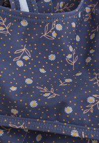 Marinblått tyg med blommönster som har vita prästkragar och gula prickar; mjuk textur med rosa och gröna accenter i ett upprepat mönster.