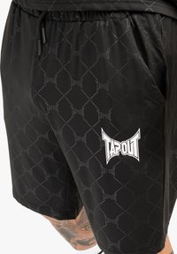 Melnas sporta šorti ar ģeometrisku rakstu un balto "TAPOUT" logotipu. Izgatavoti no viegla materiāla ar elastīgu jostu.