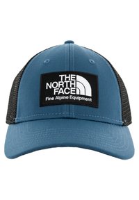 Kék és fekete trucker sapka, szilárd elülső panellel, hálós hátsó résszel, és egy fehér logópatch-el, amelyen a "The North Face" és a "Fine Alpine Equipment" felirat látható.