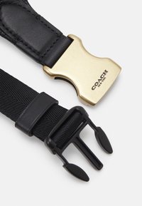 Sangle en tissu noir et cuir avec boucles dorées et noires, boucle dorée avec logo "Coach New York".