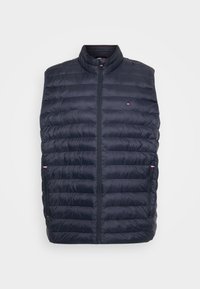 Gilet matelassé marine avec col haut, design matelassé, fermeture éclair avant et deux poches latérales. Présente des accents de logo sur la poitrine.