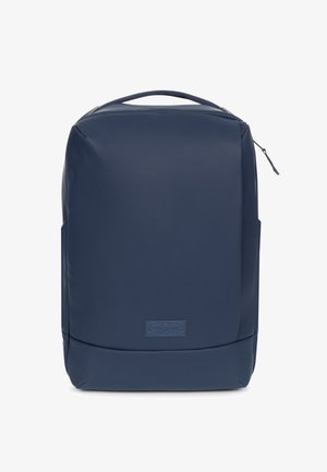Mochila azul marino hecha de material impermeable, con un diseño rectangular elegante, asa superior y un pequeño parche con logo en la parte frontal.